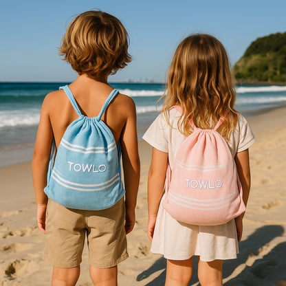 Two children on a beach with blue and pink drawstring bags labeled 'TOWLO'.