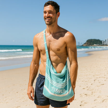 Man on a beach with a towel draped over his shoulder, featuring the 'TOWLO' brand.