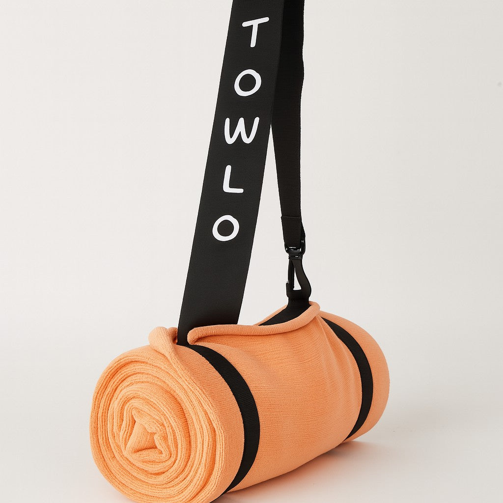 towlo peach beach towel rolled up with black shoulder strap on white background